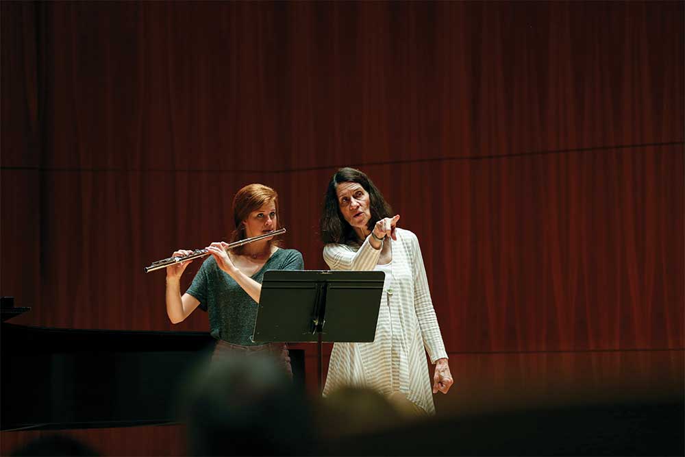 instructor assisting student playing the flute