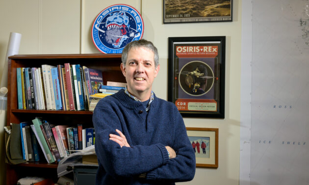 Kevin Righter in his office, with OSIRIS-REX memorabilia on the walls behind him.